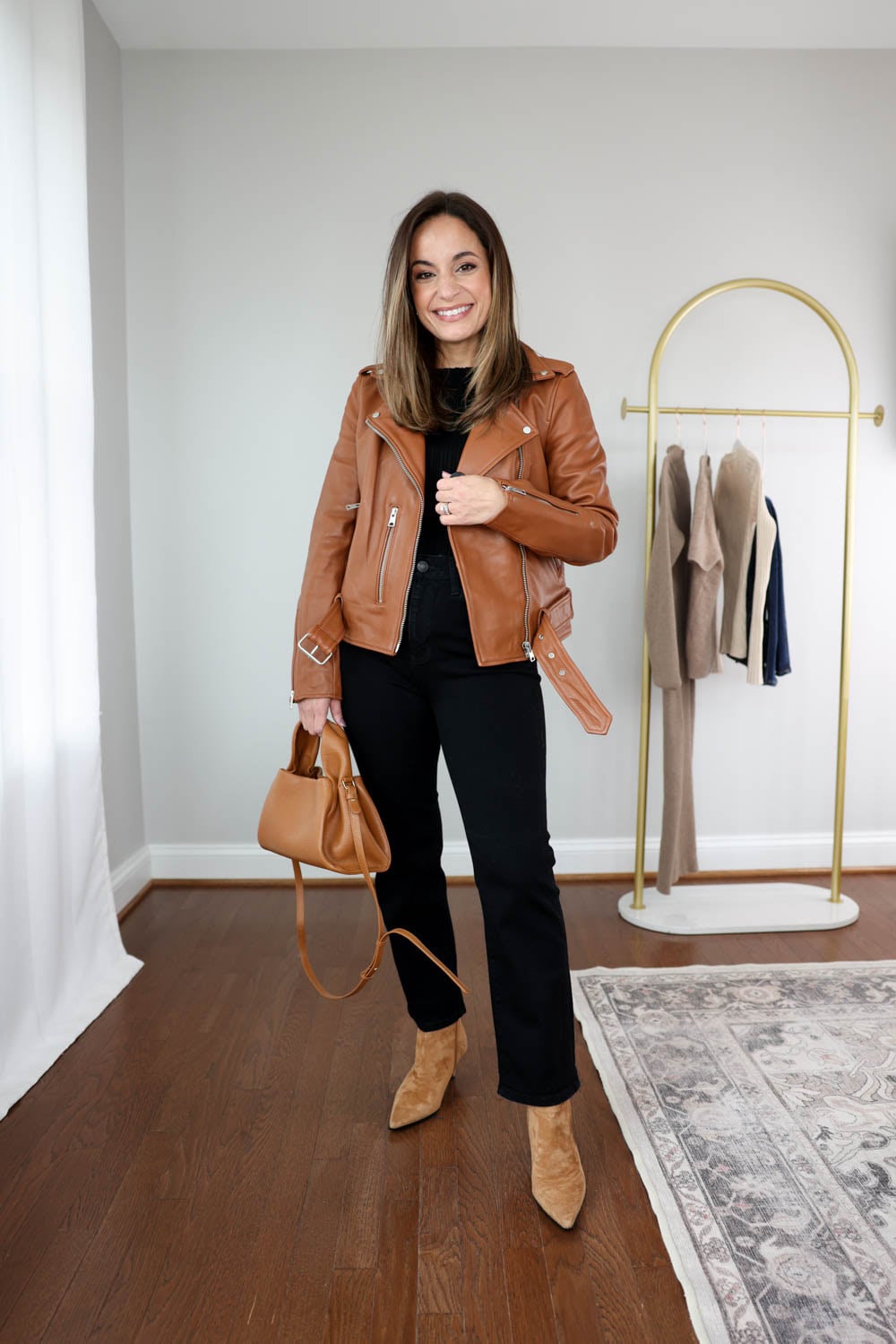 Brooke of Pumps and Push-Ups wearing the Quince Motorcycle Leather Jacket with Bella Straight Petite Jeans and an all-black base, styled with cognac accessories for a petite-friendly fall look.